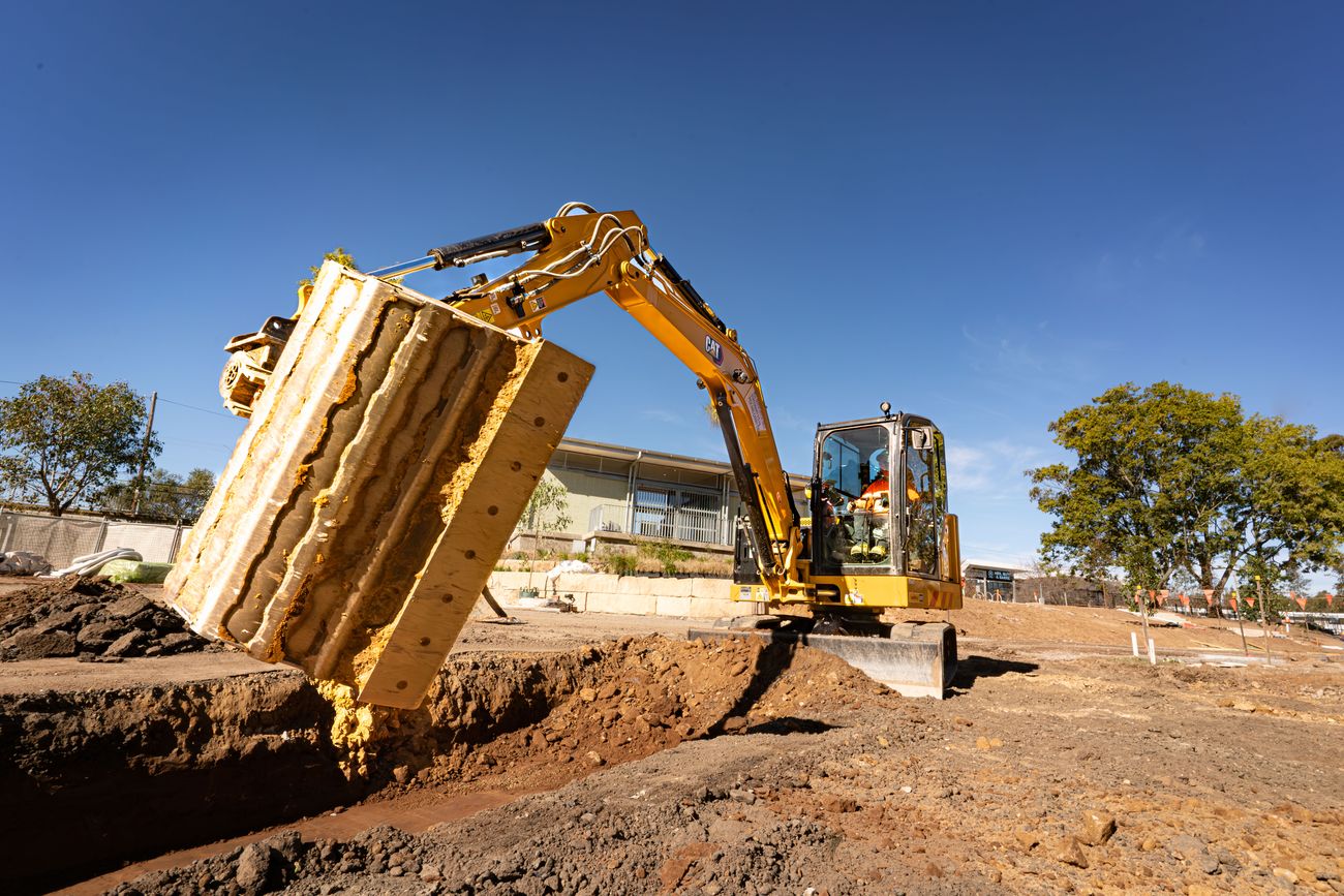 Excavator tilting a large bucket on a worksite with an Attach2 tilt coupler